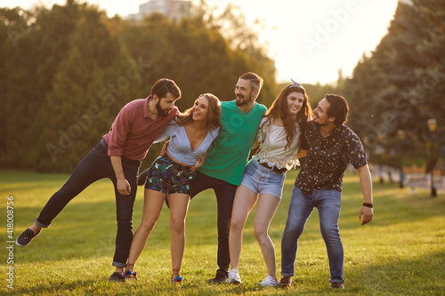 Happy student friends spending time together outdoors. Young hipsters having great time in countryside