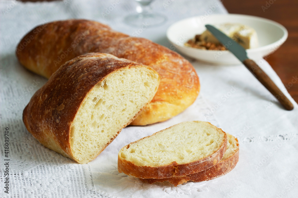 Ciabatta, cheese and nuts on a wooden table.