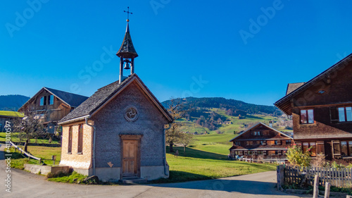 kleine Holzkapelle zwischen alten, traditionellen Bauernhäusern