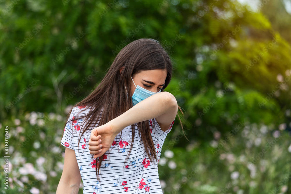 How to sneeze correctly. Woman with protective mask sneezes on the elbow. Concept of not spread of the virus. How to sneeze correctly. Woman with protective mask sneezes on the elbow. Concept of not spread of the virus.