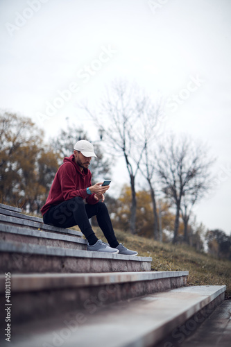 Athletic sporty man training in hoodie sweatshirt in urban city park.