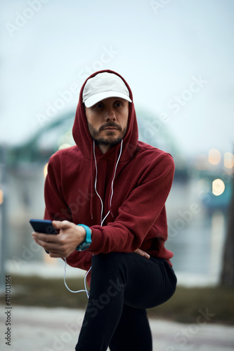 Athletic sporty man training in hoodie sweatshirt in urban city park.