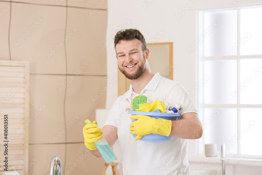Young man with cleaning supplies in bathroom Young man with cleaning supplies in bathroom