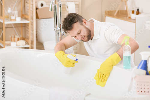 Young man cleaning his bath...