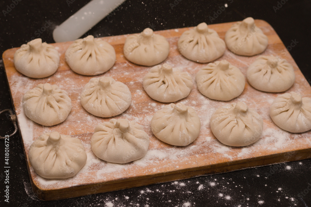 Slender rows of uncooked Georgian khinkali with a rolling pin lying next to it