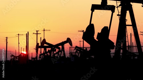 The sun rises behind oil pumps in California