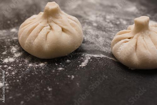 Georgian khinkali sprinkled by flour on a black table. Side view