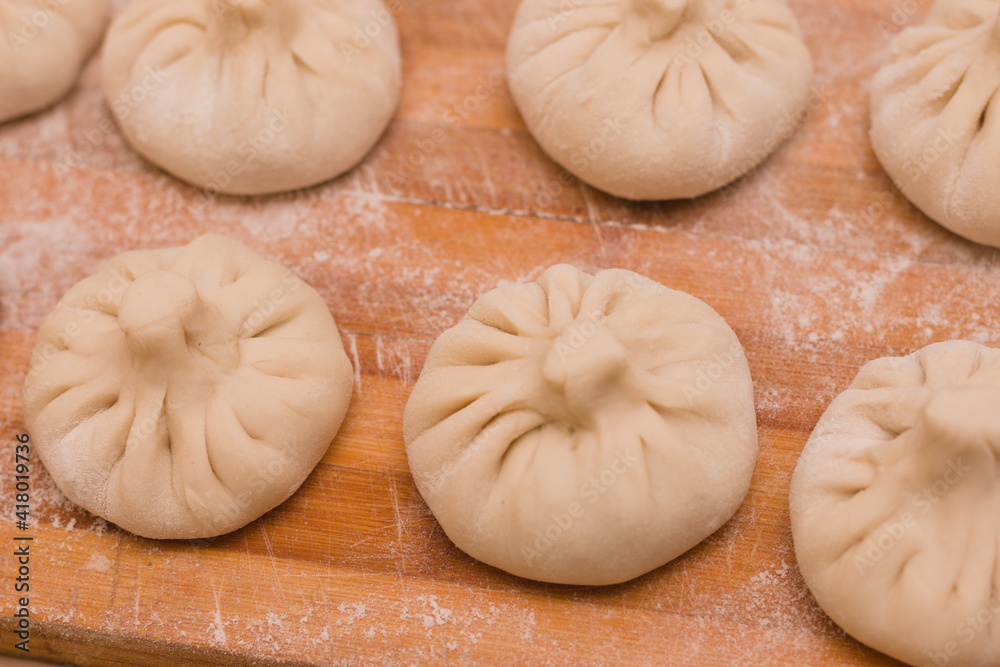 Homemade khinkali ready to cook on a wooden board