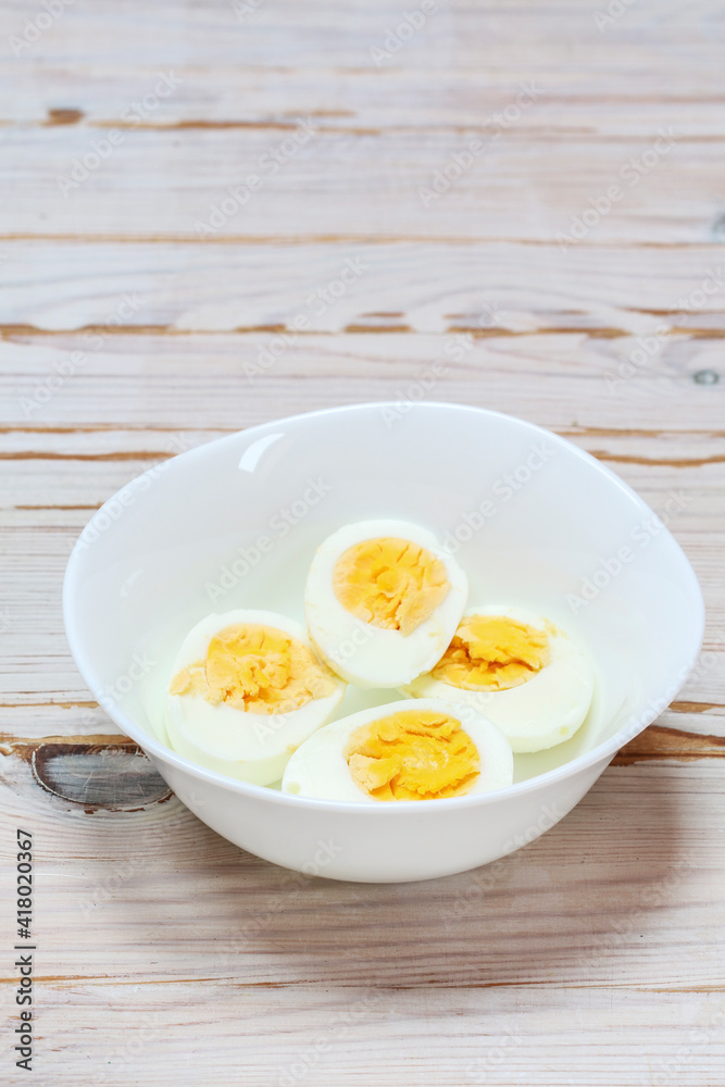 Hard-boiled eggs in a white bowl on wooden table. Hard-boiled eggs in a white bowl on wooden table.