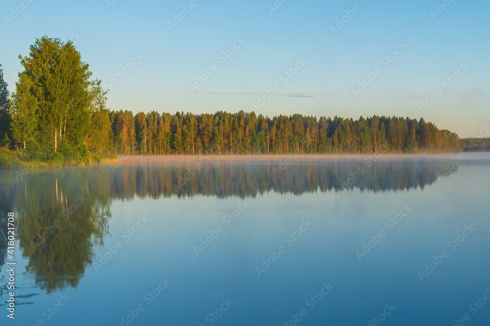 Sunrise and morning fog over the Roshchinsky lake near the walls of the monastery. Holy Trinity Alexander Svirsky Monastery in the Leningrad region, known for architectural monuments.