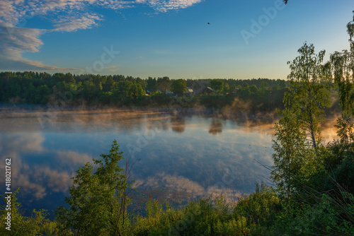 View of the adjacent village, located on the shore of Roshchinsky lake in the morning and sunrise. Holy Trinity Alexander Svirsky Monastery in the Leningrad region, known for architectural monuments.