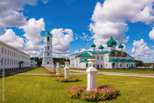 The courtyard of the monastery with a view of the Transfiguration Cathedral and the Bell Tower, sunny sky with large clouds. Holy Trinity Alexander Svirsky Monastery in the Leningrad region.