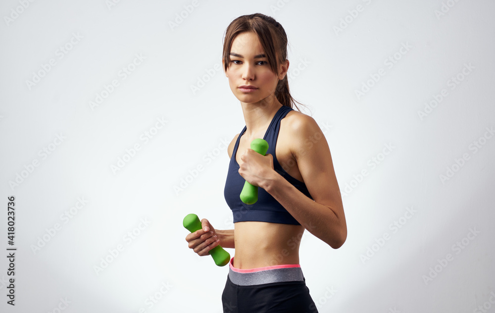 energetic sportswoman is engaged in active exercises on a light background and dumbbells towel fitness energetic sportswoman is engaged in active exercises on a light background and dumbbells towel fitness