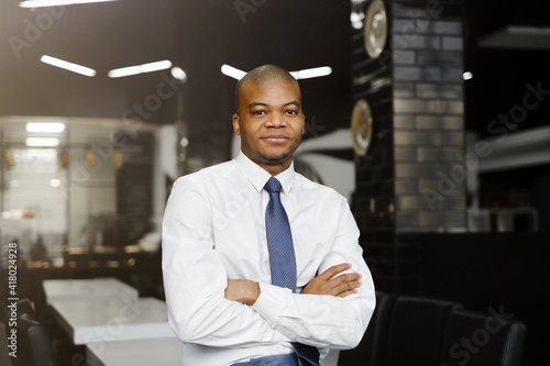 portrait of an African-American businessman dressed in a white shirt, standing in an office with a dark interior
