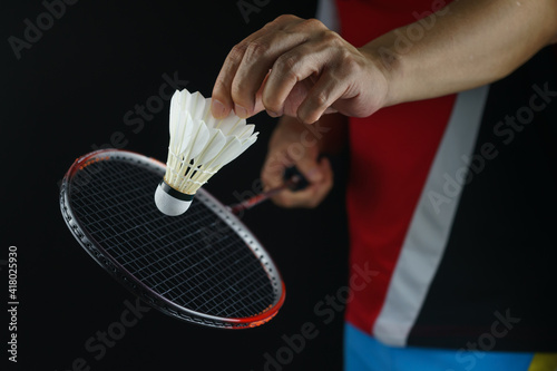 A badminton player postures the face of the racket to serve the badminton ball in the match
