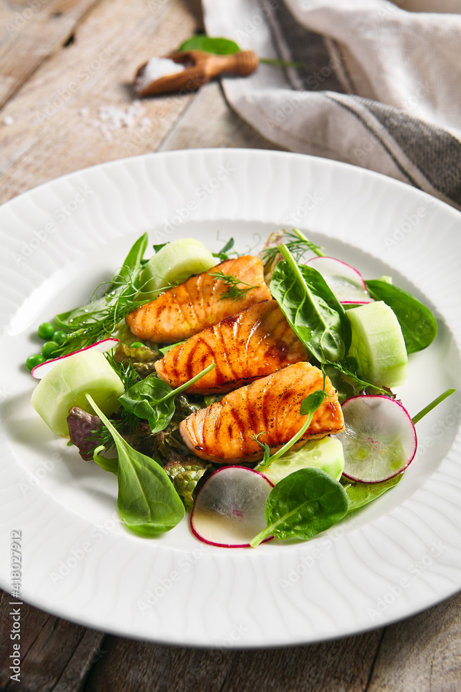 Salmon Salad with Fresh Vegetables. White plate with healthy fish food on wooden table. Healthy, Vegetarian, Restaurant rustic food concept. Salmon Salad with Fresh Vegetables. White plate with healthy fish food on wooden table. Healthy, Vegetarian, Restaurant rustic food concept.