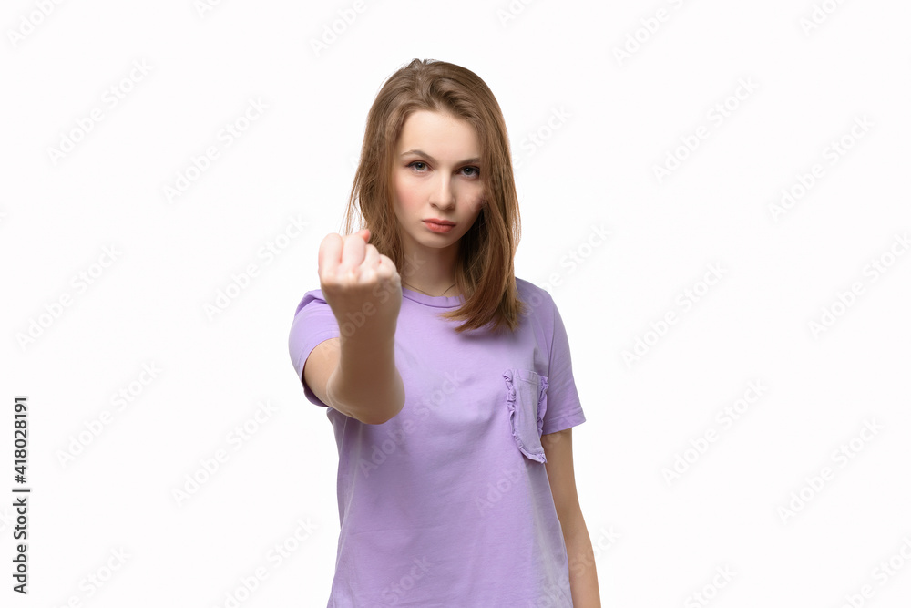 Angry serious girl looking at camera showing fist isolated on white background Angry serious girl looking at camera showing fist isolated on white background