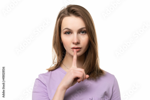 close up young pretty woman is pressing finger to lips, making silent gesture asking to keep secret, says shush or hush