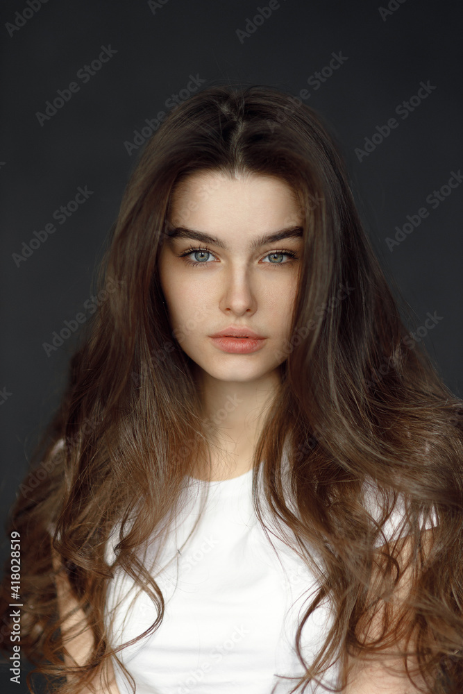 Close-up portrait of a young beautiful woman, on a dark background. Beauty portrait of a girl, studio tests. Close-up portrait of a young beautiful woman, on a dark background. Beauty portrait of a girl, studio tests.