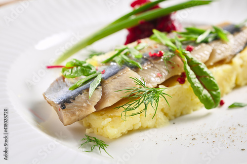 Herring Fish and Mashed Potatoes Plate. Garnished with green onion and beet salad. White restaurant plate on grey table. Salad, Healthy, Appetizer rustic food concept.