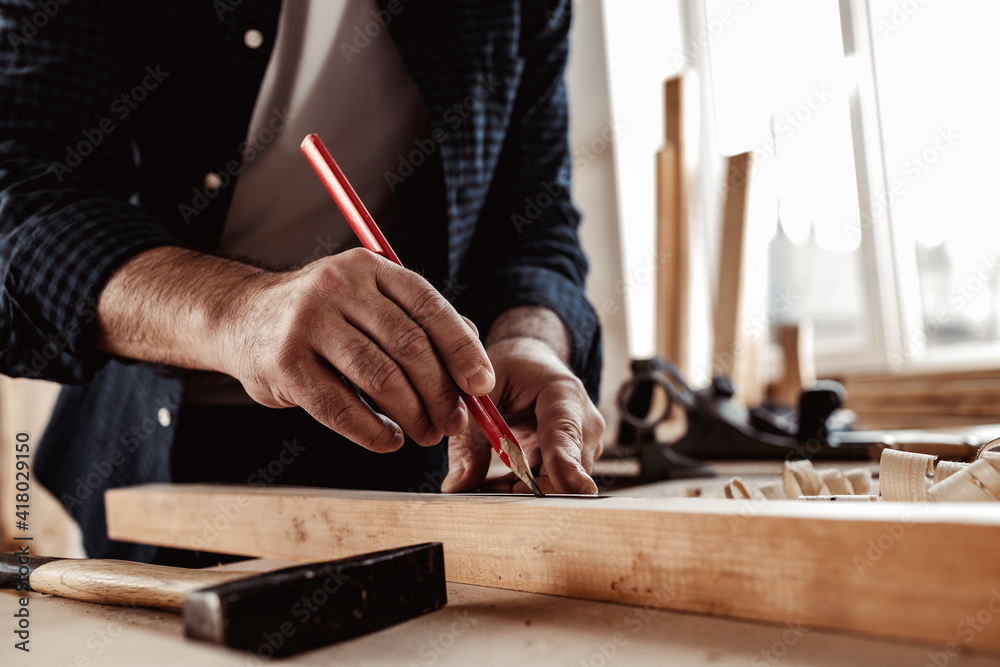 Carpenter makes pencil marks on a wood plank Carpenter makes pencil marks on a wood plank