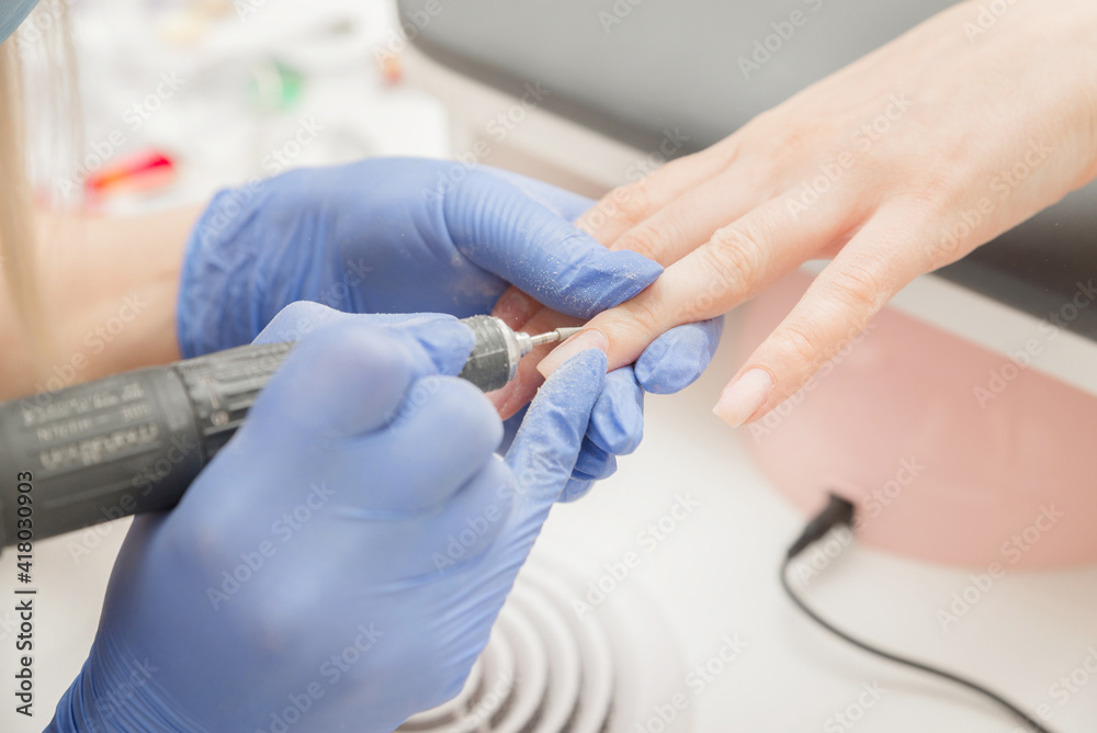 Manicurist treats the cuticle to the client while making a manicure, close-up