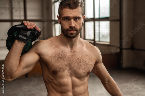 Strong sportsman exercising with kettlebell in gym