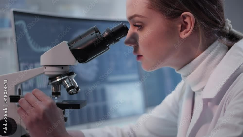 Female doctor working in laboratory. Studying medical samples. Looking through glassware and monitor Female doctor working in laboratory. Studying medical samples. Looking through glassware and monitor