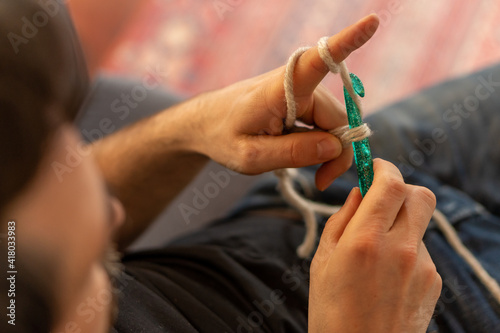 Fotografie Man's hand with a big and green acrylic crochet needle learning a new hobby