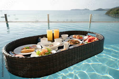 Breakfast set in tray in swimming pool, floating breakfast in tropical resort villa with ocean view.