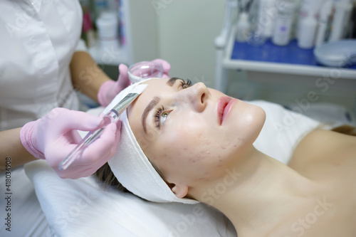 Cosmetologist does face peeling of a beautiful woman. Women s cosmetology in the beauty salon