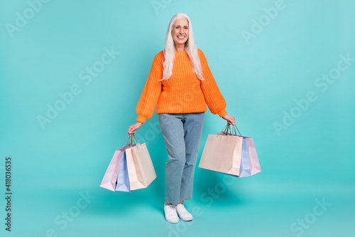 Full length photo of charming happy old woman hold shopping bags nice sale isolated on teal color background