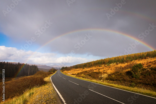 Autumn landscape in Highlands, Scotland, United Kingdom. Road with beautiful and colourful rainbow in background. © danmir12