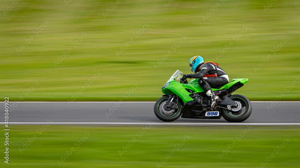 A panning shot of a racing motorbike as it circuits a track.