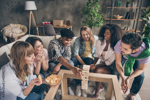 Photo portrait of friends playing game wooden blocks eating chips laughing excited on weekend