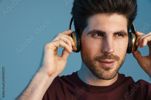Pleased handsome man listening music with wireless headphones