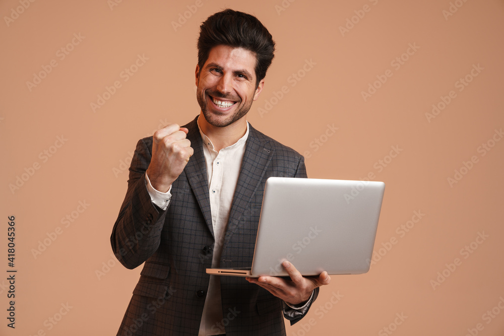 Excited man making winner gesture while working with laptop Excited man making winner gesture while working with laptop