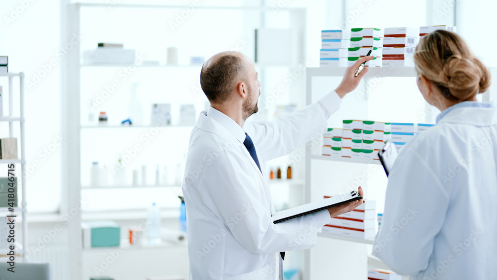 male pharmacist making notes on the clipboard .