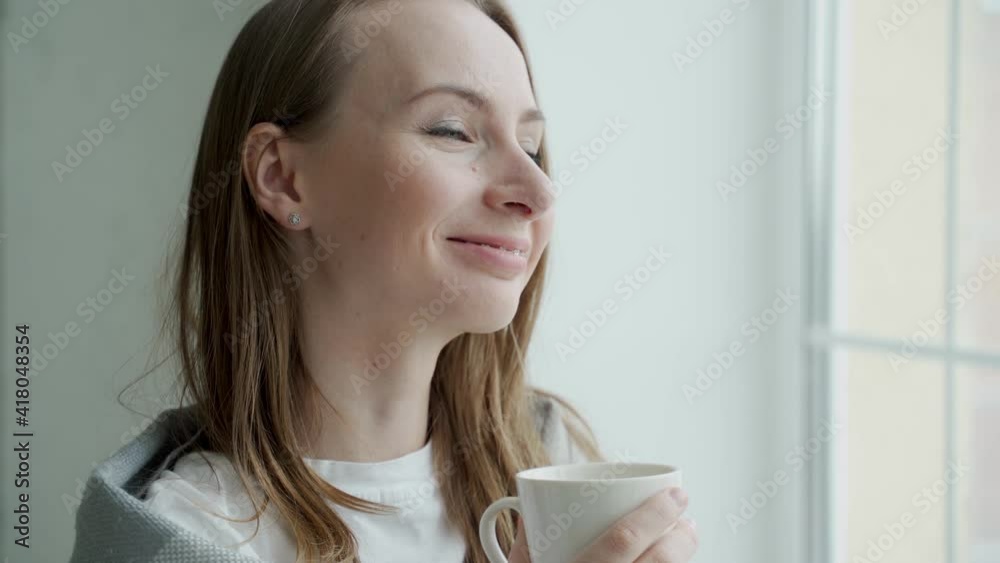 Woman thinking holding a mug beside a window at home Woman thinking holding a mug beside a window at home