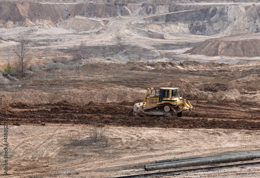 Dozer has been recovering the landscape around the open pit. Process of restoring land. Bulldozer at mine reclamation once mining sand is completed. Clearing land. Soft focus Dozer has been recovering the landscape around the open pit. Process of restoring land. Bulldozer at mine reclamation once mining sand is completed. Clearing land. Soft focus