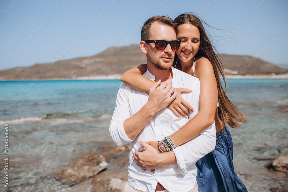 Portrait of a woman embracing her man from behind on seaside background Portrait of a woman embracing her man from behind on seaside background