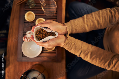 Female hands holding bowl of dried tea leaves