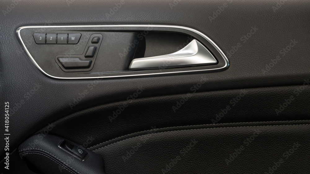 Modern car door handle with seat control knobs.