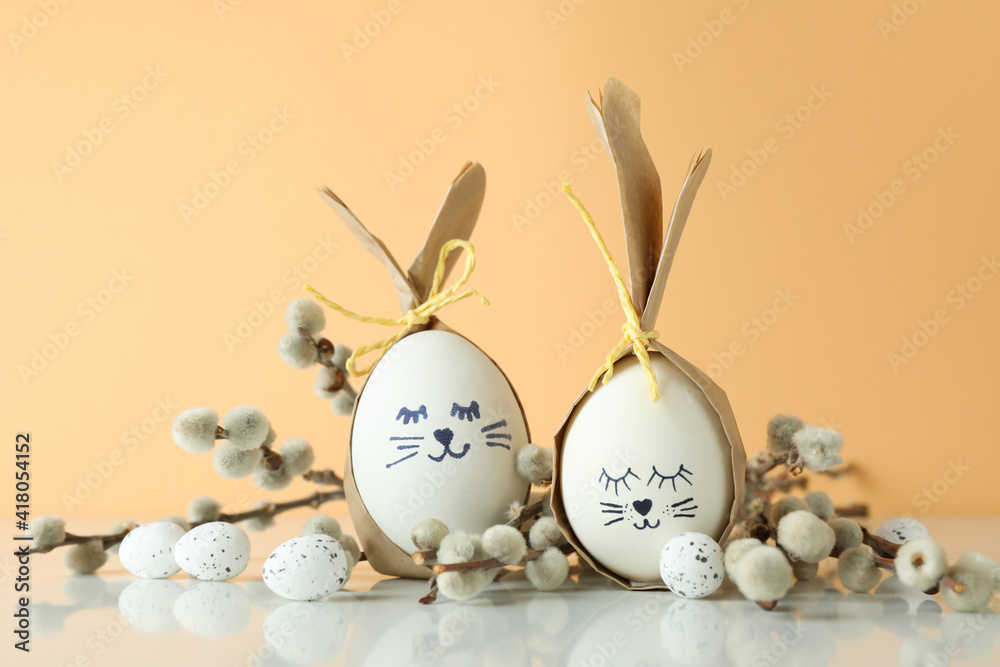 Easter bunnies made of eggs, quail eggs and catkins against beige background Easter bunnies made of eggs, quail eggs and catkins against beige background