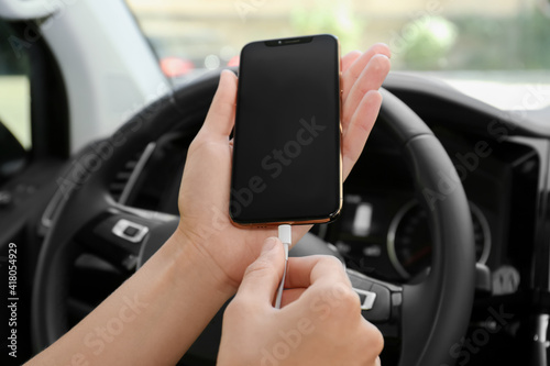 Person charging phone with USB cable in car