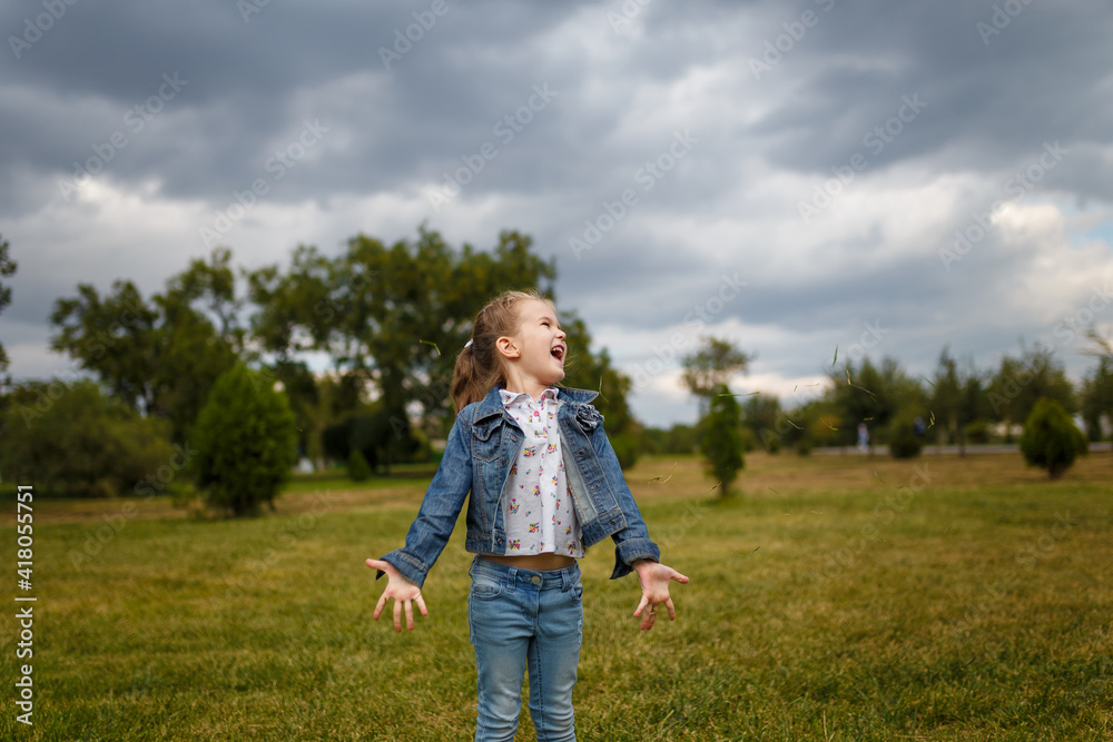 Little girl jumping and throwing green grass on lawn in spring park. Happy joyfull emotion, carefree childhood, outdoors activity Little girl jumping and throwing green grass on lawn in spring park. Happy joyfull emotion, carefree childhood, outdoors activity