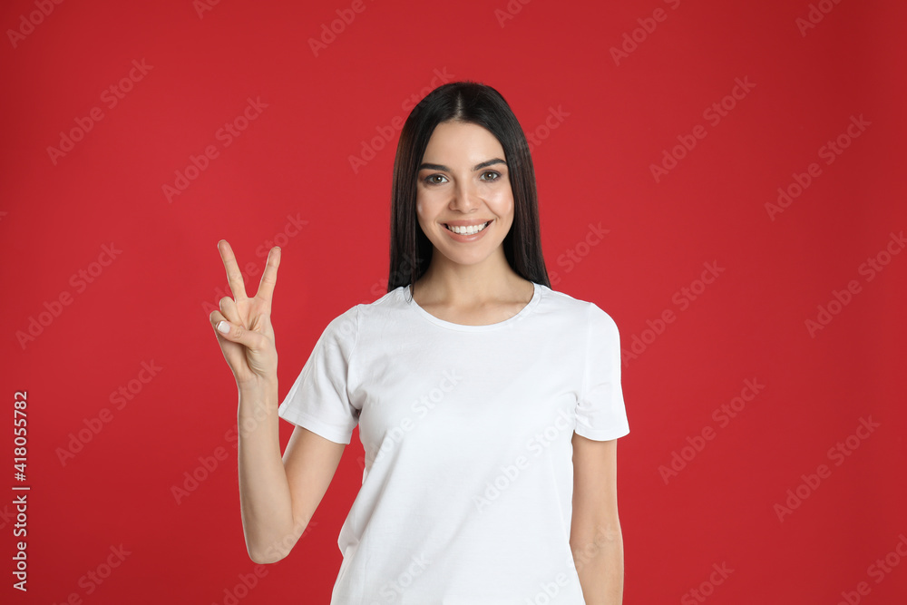 Woman showing number two with her hand on red background Woman showing number two with her hand on red background
