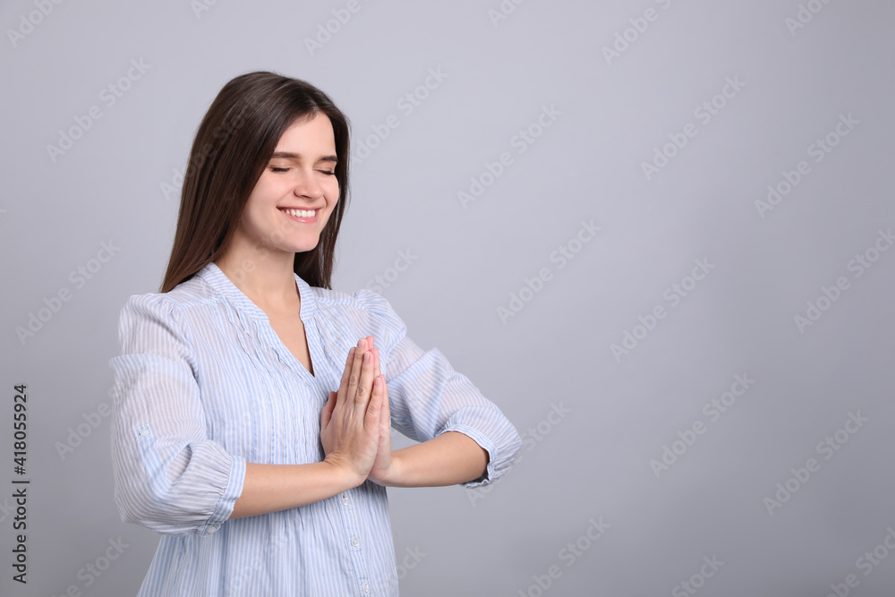 Young woman meditating on grey background, space for text. Stress relief exercise Young woman meditating on grey background, space for text. Stress relief exercise