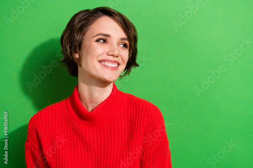 Photo of optimistic nice brunette hairdo lady look empty space wear red sweater isolated on bright green color background