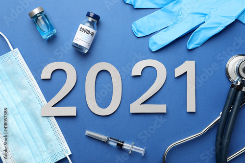 Flat lay composition with coronavirus vaccine and number 2021 on blue background